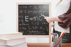 The teacher is explaining complicated physics theories to students on a blackboard. 